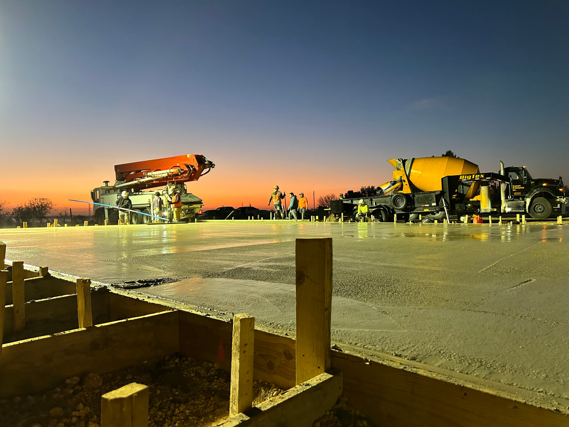Sunrise concrete pour with pump truck and mixer on a slab