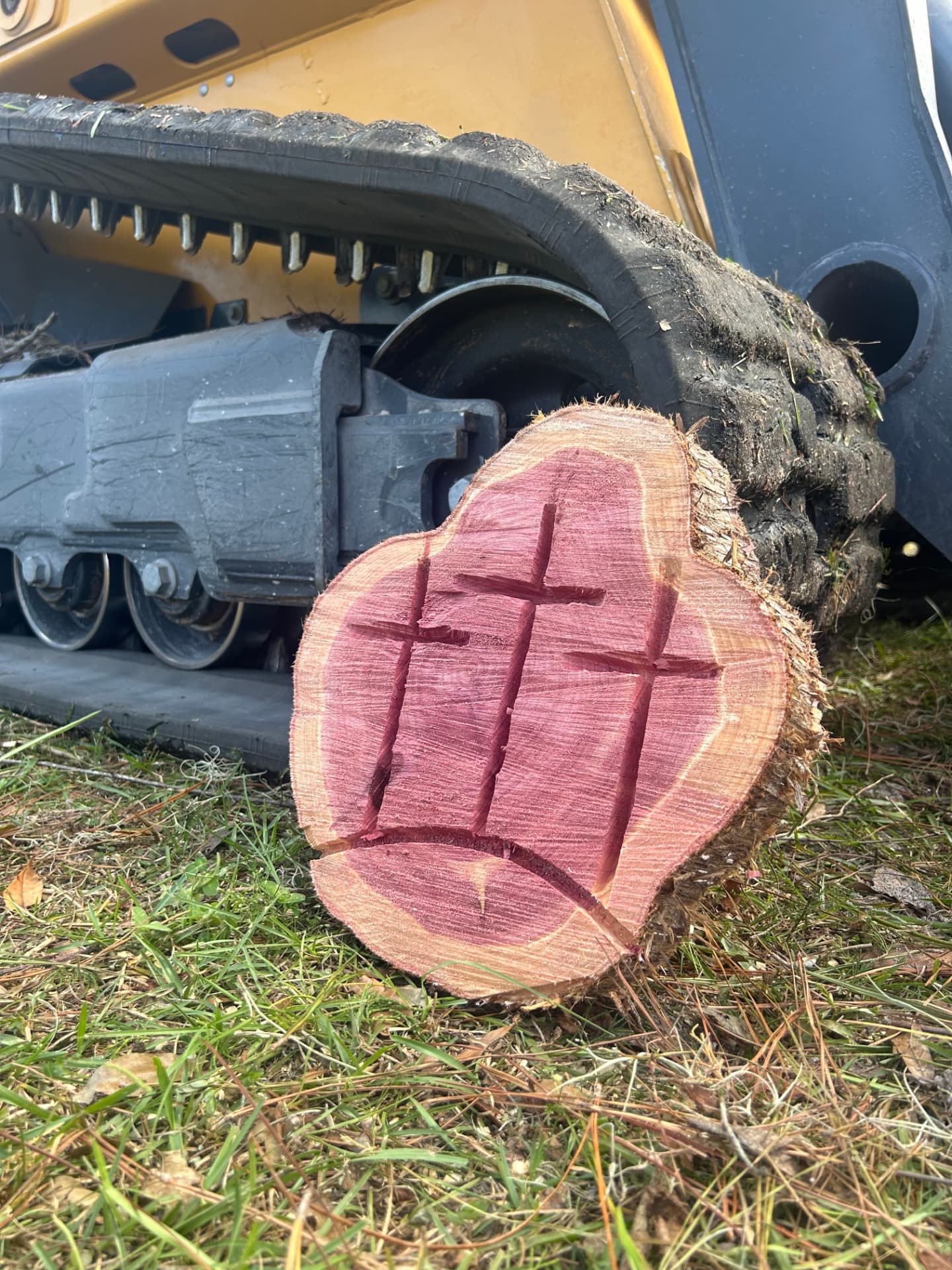Cedar log round carved with three crosses beside a track loader