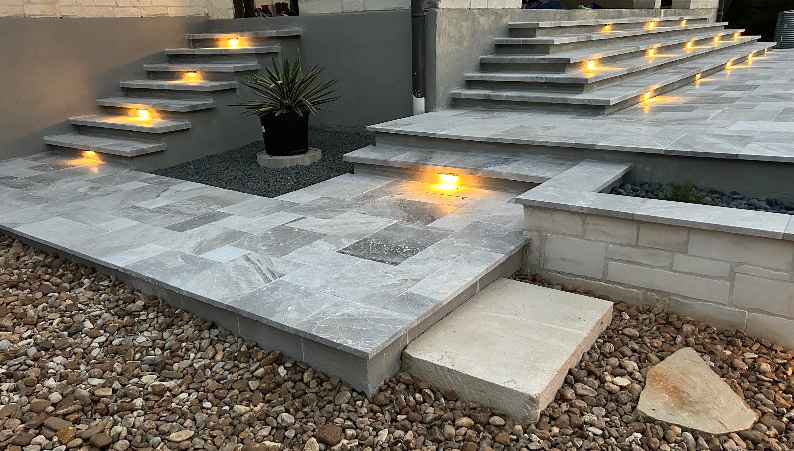 Lit stone patio steps and paver landing at dusk